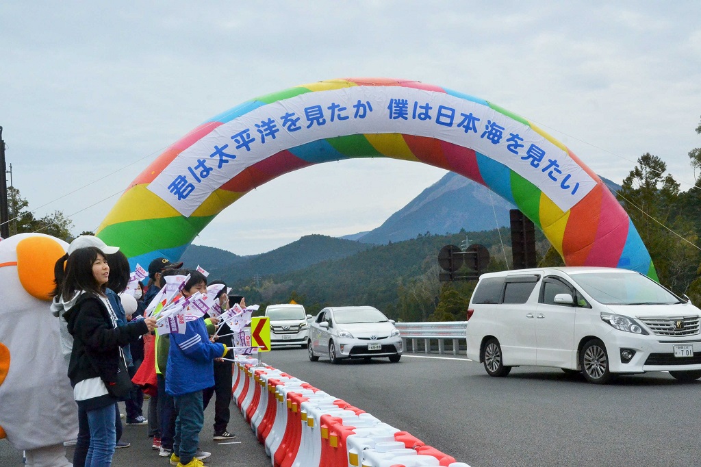 富沢ＩＣで開通パレードの車両を出迎える地元住民ら＝２０１９年３月１０日午前１１時１０分ごろ、山梨県南部町（写真の一部を加工しています）